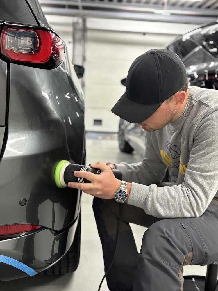 Un passionné polit la carrosserie d’une voiture avec une polisseuse
